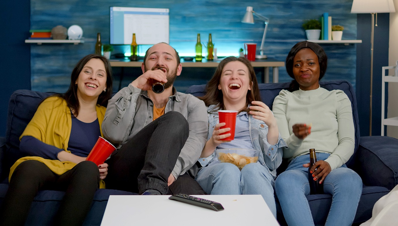 Gruppe auf Sofa vor dem TV lacht